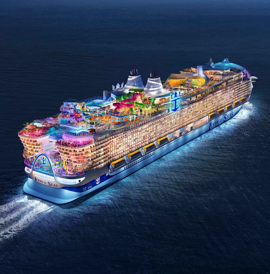 Icon of the Seas cruise ship illuminated at night with colorful water slides and pools.